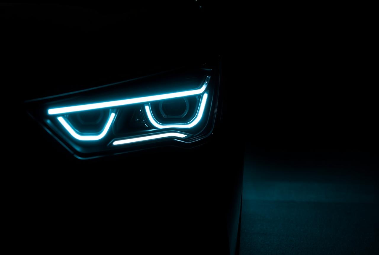 Modern LED car headlight glowing with a sharp light signature in the dark
